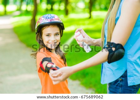 Mother spraying insect repellents on skin girl