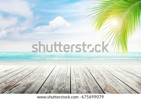 Empty wooden table and palm leaves with party on beach blurred background in summer time. Royalty-Free Stock Photo #675699079