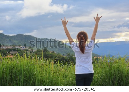 Young woman with charming show hand I Love You sign stands on nature
