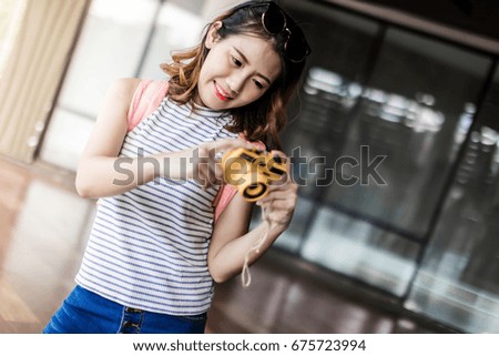 Beautiful Asian female tourist posing with a camera on the outdoor. Hipster young girl with backpack taking retro photo, traveler photographer enjoying summer. Travel photographer concept