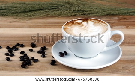 Latte art and cappuccino with Rosetta leaf and flowers made from milk on the wood table with roasting coffee beans. Beverage and breakfast or food and drink menu with hot coffee at the cafe shop.
