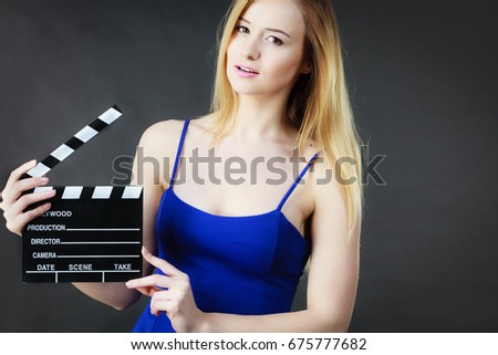 Woman holding professional film slate, movie clapper board. Hollywood production objects concept. Studio shot on black background.