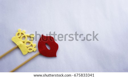 Top or flat lay view of Photo booth props a red lips and a yellow crown on a white background flat lay. Birthday parties and weddings.