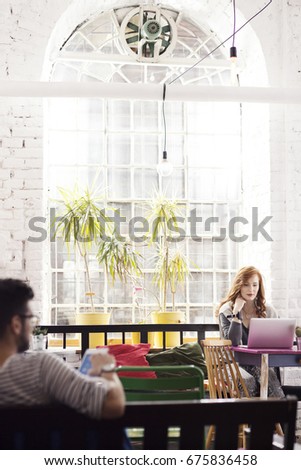 Woman working as freelancer in bright industrial interior with big window