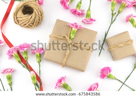 Brown gift boxes, ropes and red ribbon decorated with pink carnation flowers on white background