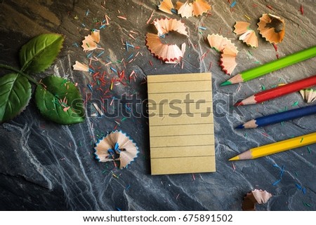 A notebook for notes with crayons and pencils. Pencil sharpener placed on a table made of stone.  Using image for education with business and lifestyle.