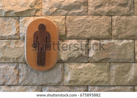 Sign of male toilet figure on textured marble wall