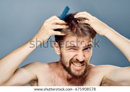 A man combs his hair against a gray background                               