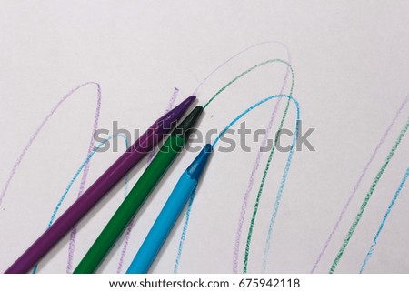 Blue, green and purple pencils leave a mark on the paper