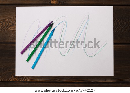 Blue, green and purple pencils leave a mark on the paper