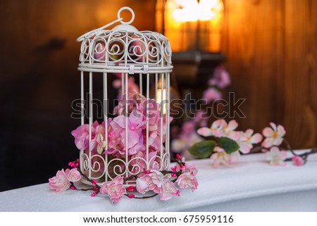 Vintage cage with flowers on a marble parapet, close-up, studio photography.