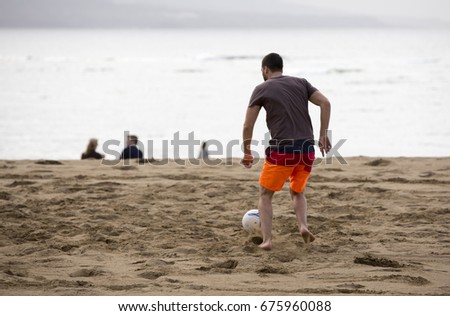 horizontal friends playing football in the beach in canary island
