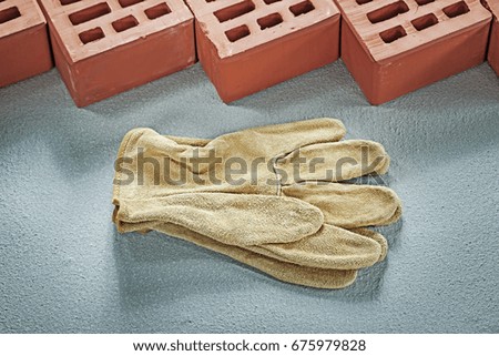 Orange bricks leather protective gloves on concrete surface buil