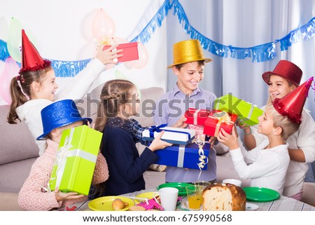 Smiling american children giving presents to little boy during party