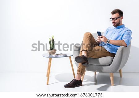 smiling businessman in eyeglasses using smartphone isolated on white Royalty-Free Stock Photo #676001773