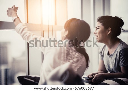 two beautiful friend asian woman with hppiness and joyful moment together with talking and chatting on smartphone near window with daylight