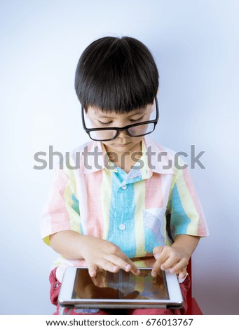 Nerdy Asian kid is playing education game on tablet on white background