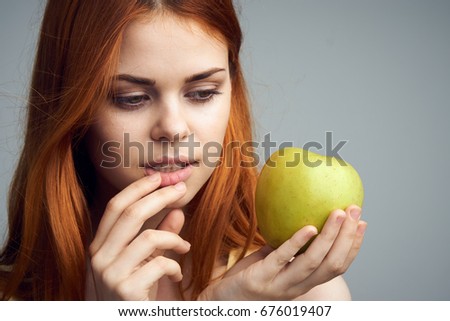 Beautiful young woman on a gray background holding an apple.