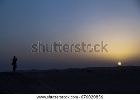 Man taking pictures of sunset in the middle of desert of dubai, United Arab Emirates