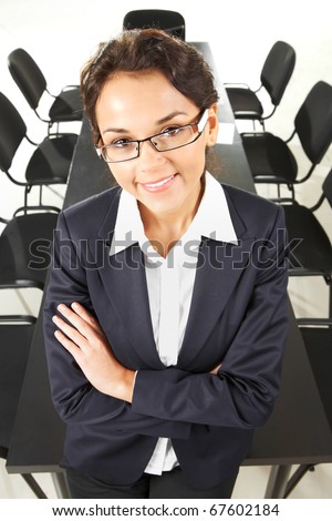Portrait of happy leader with two rows of chairs along table at background