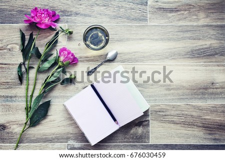 Tea, clean notebook and flower on pink table from above. Female working desk. Cozy breakfast. Flat lay style.