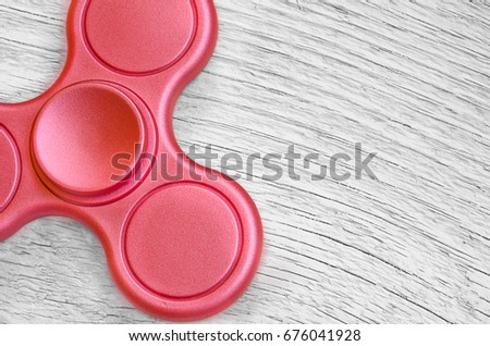 Red fidget spinner on background white wood. Stress relieving toy.