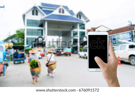 Man use mobile phone, blur image of the frontier border checkpoint Mae Sai, Chiang Rai THAILAND as background.