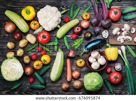 
Vegetables and mushrooms on a dark wooden rustic table. 
Cabbage, cauliflower, green peas, tomatoes, peppers, cucumbers, eggplant, beets, onions, radish, potatoes. Royalty-Free Stock Photo #676095874