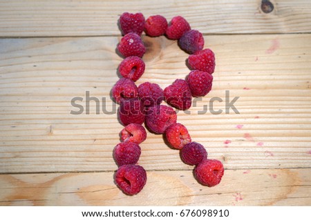 Alphabetical letter R made of raspberries on a white background

