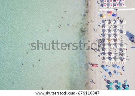 Aerial view of the amazing beach with colorful umbrella and people who swim.
