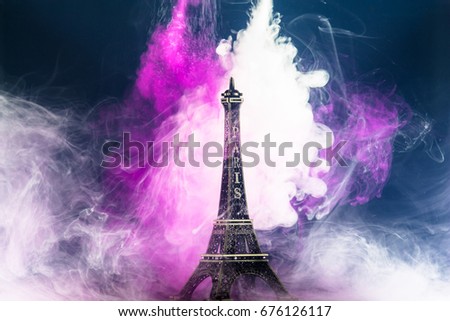 Color drop in water, Eiffel tower model and ink swirling in water that blue background. selective focus.