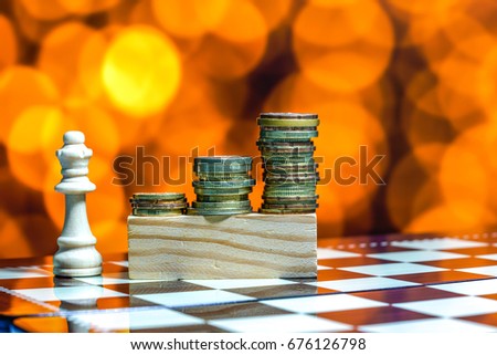 Coins and pieces of chess with bokeh background.