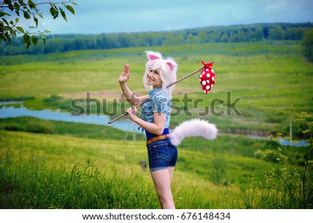 A girl cat says goodbye. The girl in short shorts waving his hand against the background of the field.
