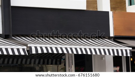 blank shop sign and striped black & white awning