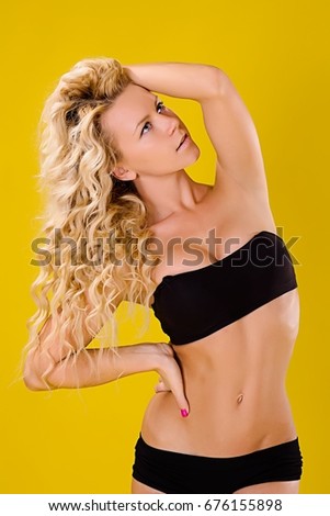 A sportive young girl in a dancing uniform for a plastic strip pose her head thrown back, picking up her hair with her hand looking up. Elegant body of a sports girl.