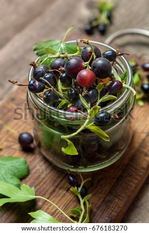 Black currant on wooden table with leaf sprig.