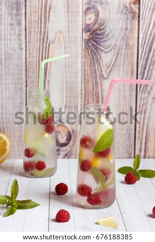 Cold cocktail with raspberries, lemon and mint. Wooden background.