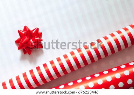 Festive background. Red wrapping roll paper for gifts. Red gift bow. Top view.