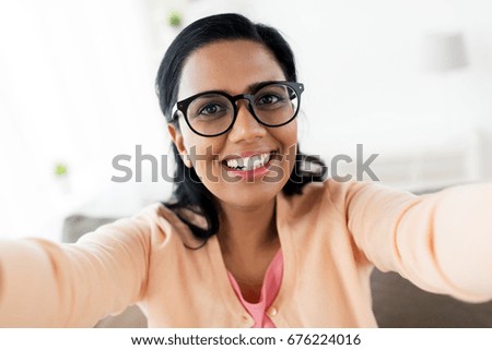 people and technology concept - happy smiling indian woman taking selfie at home