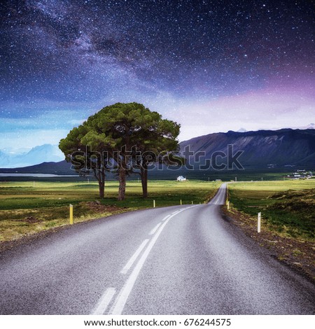 Asphalt road and lonely tree under a starry night sky and the Milky Way. Courtesy of NASA.