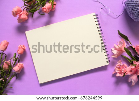 Romantic roses flat lay with blank page notebook on violet background. Romantic pink flower bouquet. White paper notepad with text place. Wedding or birthday card template. Feminine banner or mockup