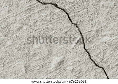 White texture of the relief surface of a painted concrete wall with one big crack, abstract background
