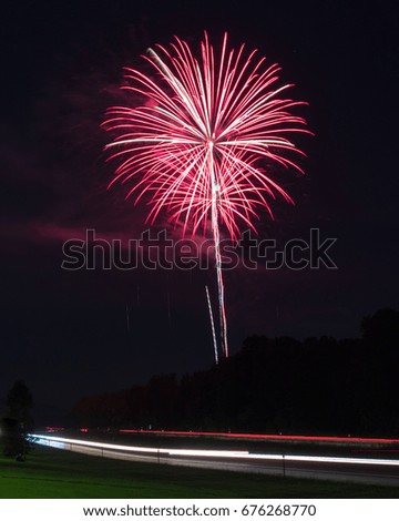 Red fireworks display with light trails from interstate.