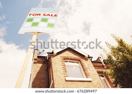 Low angle view of sale sign in front of new house against cloudy sky
