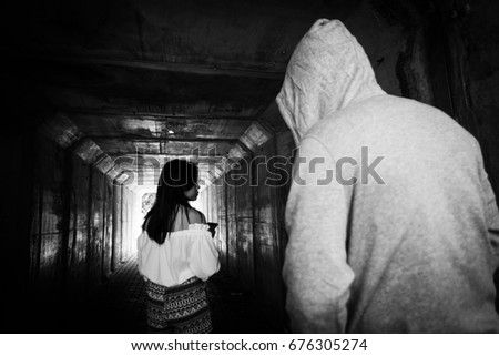Social Issues,Beautiful woman on the phone while walking in the tunnel and being stalked by stranger  Royalty-Free Stock Photo #676305274