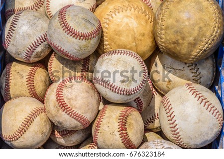 Basket of old baseballs and softballs in daylight