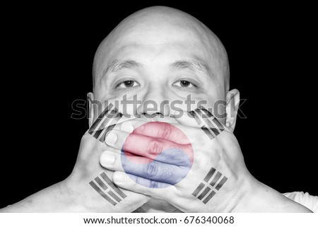 A man covering his mouth with his hand with imprint of the South Korean flag for the concept: Freedom of Speech in South Korea.