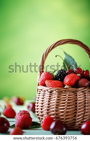 Ripe berries in a wicker basket on a wooden table.