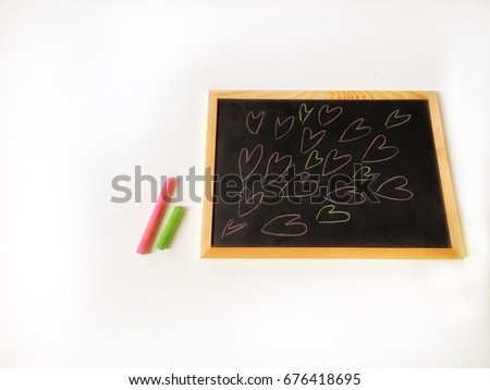 Pink and green colorful chalk put near blackboard, many cartoon heart draw in blackboard.