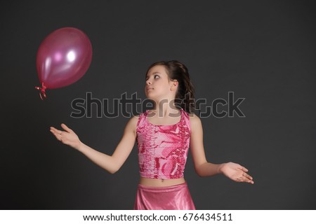Girl in pink plays in studio with pink air balloon